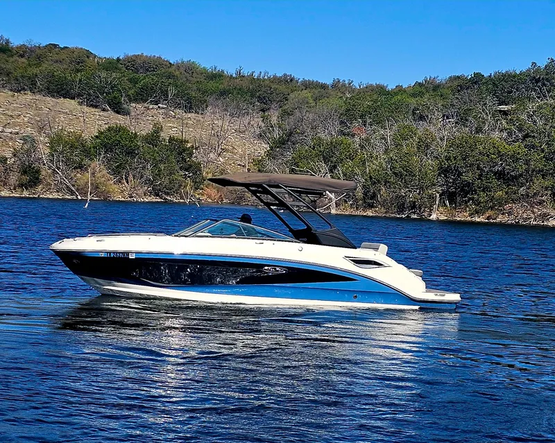 Slide: The Image of 2022 Sea Ray SDX 250 boat cruising on a serene lake with lush green shoreline. - 16