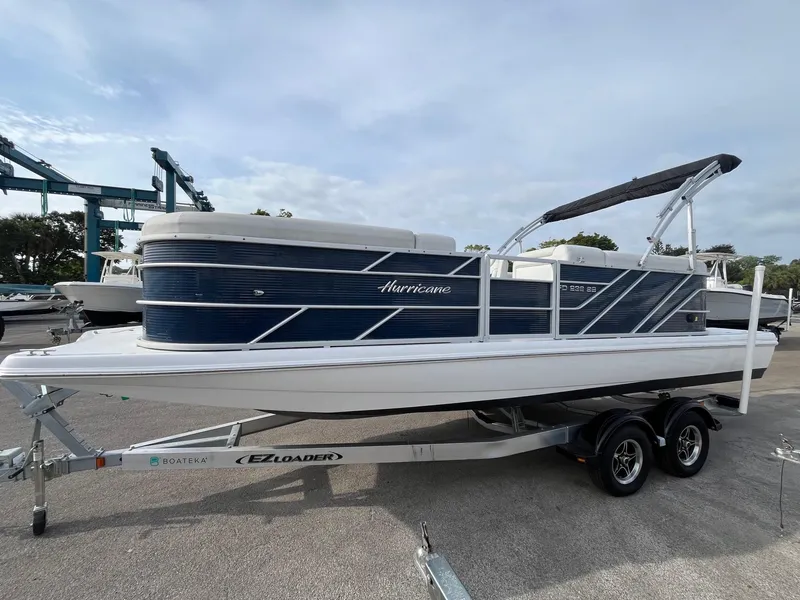Slide: The Image of 2021 Hurricane FunDeck 236SB OB boat on trailer, blue and white design, parked outdoors. - 2