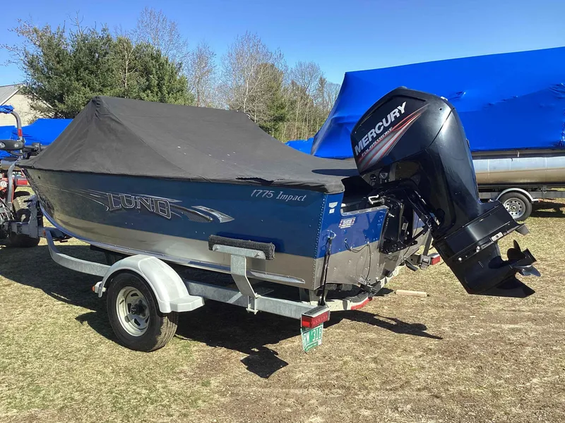 Slide: The Image of 2016 Lund 1775 Impact boat with Mercury outboard motor on trailer, covered and parked outdoors. - 4