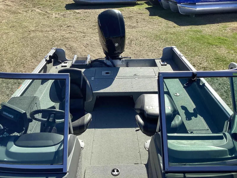 Slide: The Image of 2016 Lund 1775 Impact boat interior with seating and steering console, parked on grass. - 5