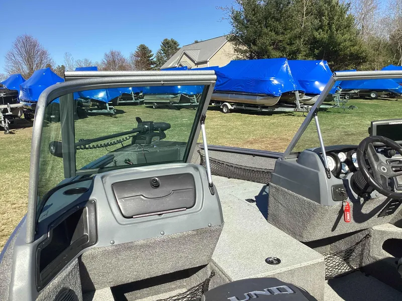 Slide: The Image of 2016 Lund 1775 Impact boat interior with steering console, parked outdoors under blue sky. - 8