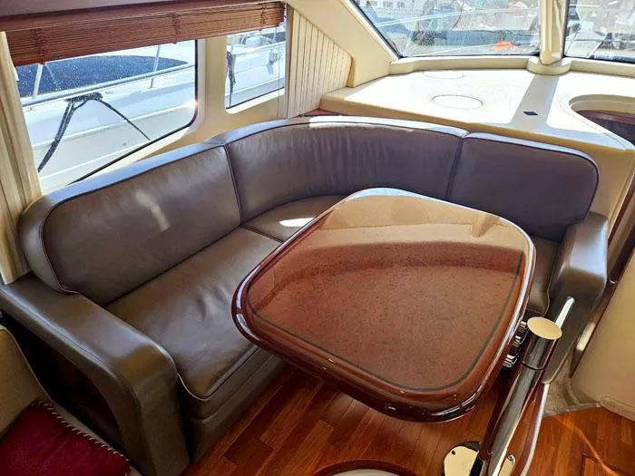 Slide: The Image of Luxurious interior of 2006 Sea Ray 44 Sedan Bridge with leather seating and wooden table. - 9