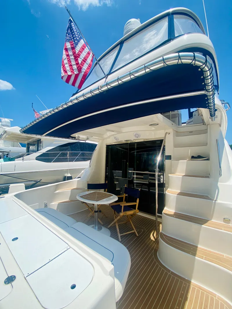 Slide: The Image of 2006 Sea Ray 580 Sedan Bridge yacht with American flag, featuring outdoor seating and stairs. - 10