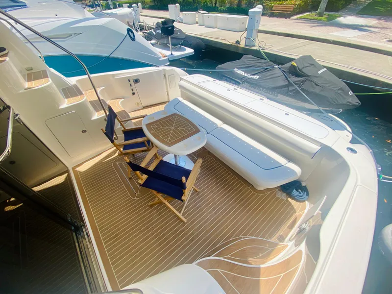 Slide: The Image of 2006 Sea Ray 580 Sedan Bridge yacht deck with seating and table, docked at marina. - 11