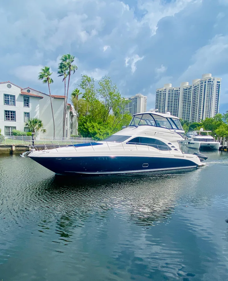 Slide: The Image of 2006 Sea Ray 580 Sedan Bridge yacht cruising near waterfront buildings. - 2