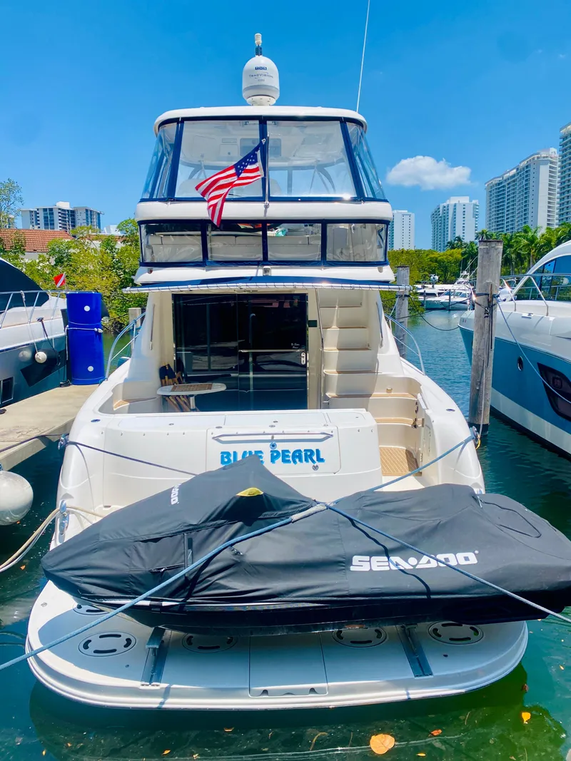 Slide: The Image of 2006 Sea Ray 580 Sedan Bridge yacht docked with jet ski, city skyline in background. - 7