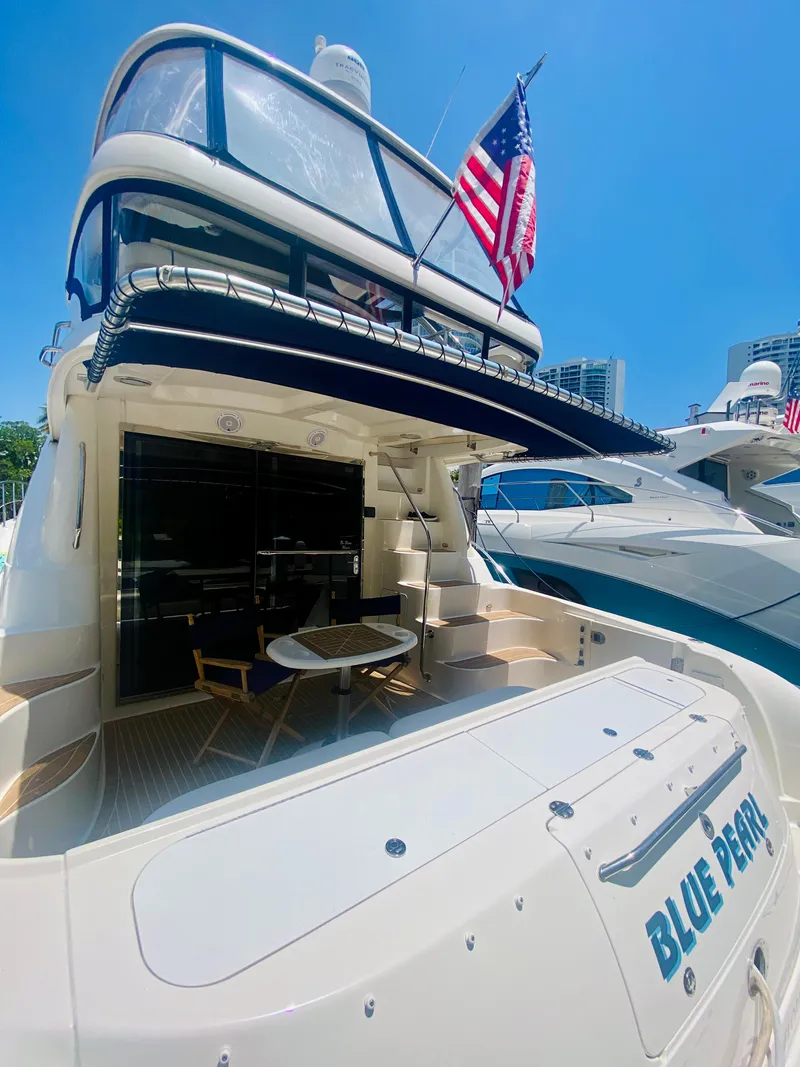 Slide: The Image of 2006 Sea Ray 580 Sedan Bridge yacht with American flag, docked under clear blue sky. - 9