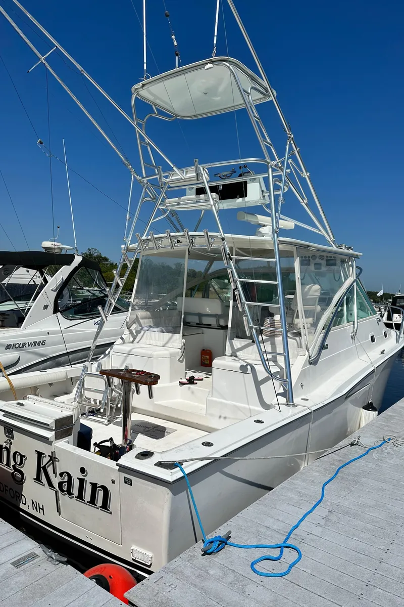 Slide: The Image of 2000 Cabo 35 Express boat docked, featuring a spacious deck and tower under clear blue skies. - 13