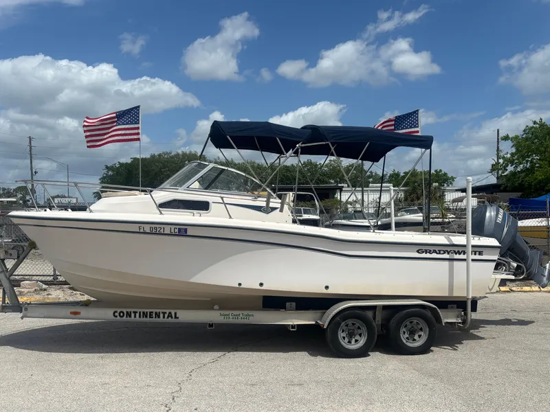 Slide: The Image of 2000 Grady-White 228 Seafarer boat on trailer with American flags, under blue sky. - 2