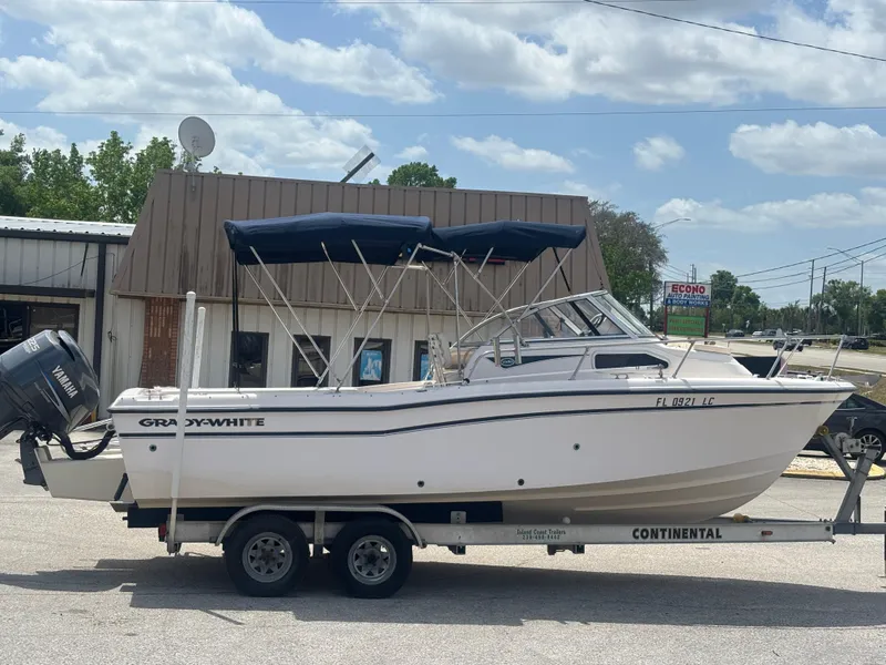 Slide: The Image of 2000 Grady-White 228 Seafarer boat on trailer, parked outdoors under cloudy sky. - 6