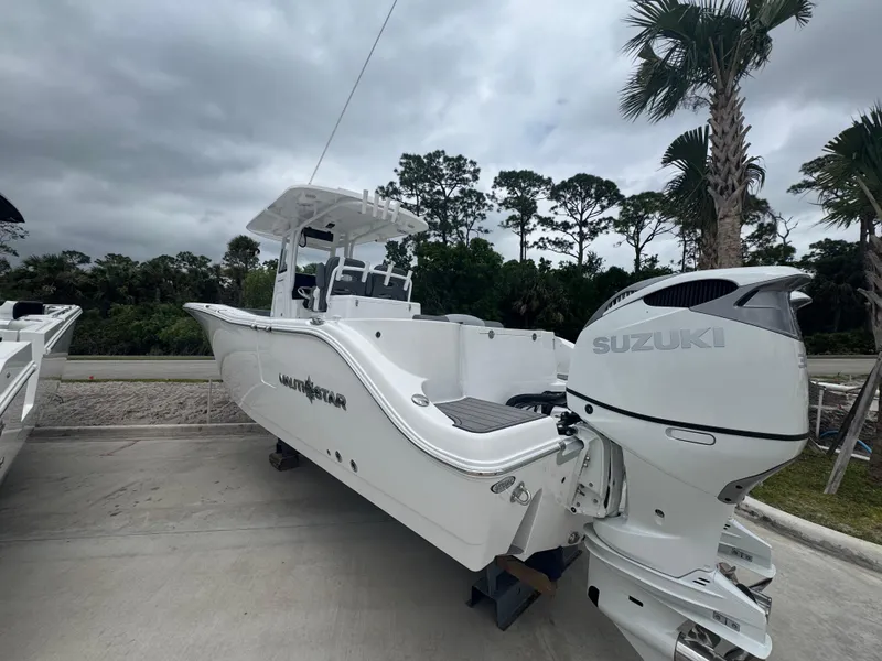 Slide: The Image of 2025 NauticStar 292 Legacy boat with Suzuki engine, parked outdoors under cloudy sky. - 4