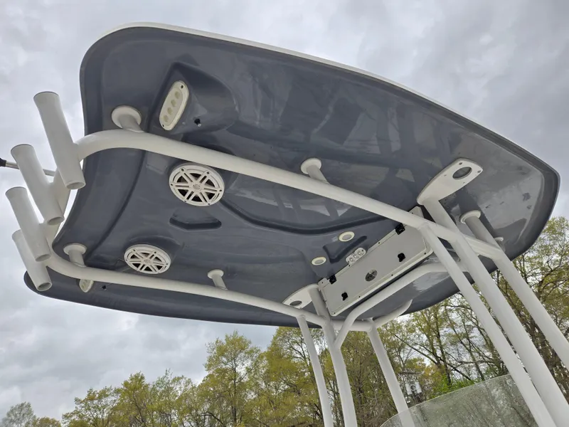 Slide: The Image of 2020 Tidewater 220 LXF boat T-top with speakers and rod holders, under cloudy sky. - 11