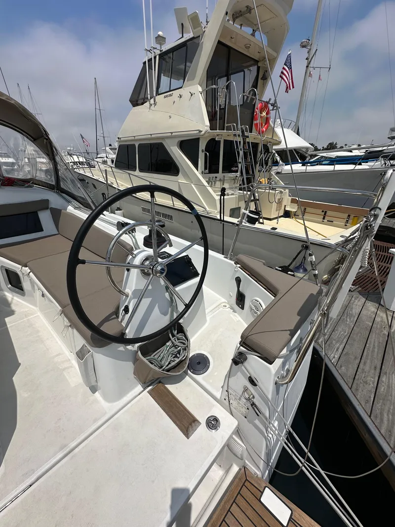 Slide: The Image of 2020 Jeanneau Sun Odyssey 410 sailboat docked at marina, featuring steering wheel and deck seating. - 21