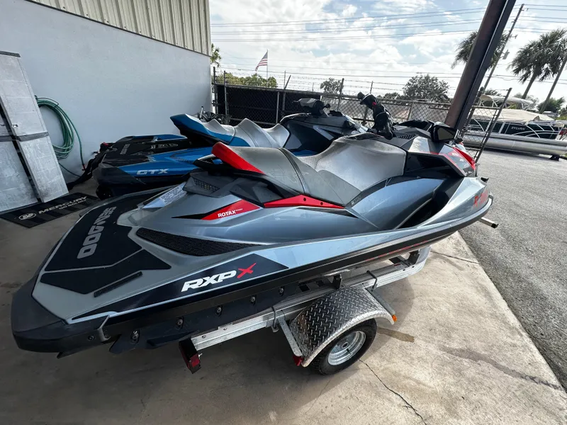 Slide: The Image of 2018 Sea-Doo RXP-X 300 jet ski on a trailer, parked outdoors. - 2