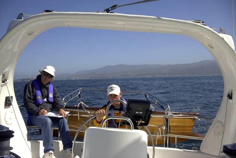 Slide: The Image of Two people sailing a 1999 Hunter 380 yacht on a sunny day. - 11