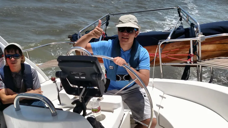 Slide: The Image of Man steering 1999 Hunter 380 sailboat, giving thumbs up, wearing sunglasses and hat. - 13
