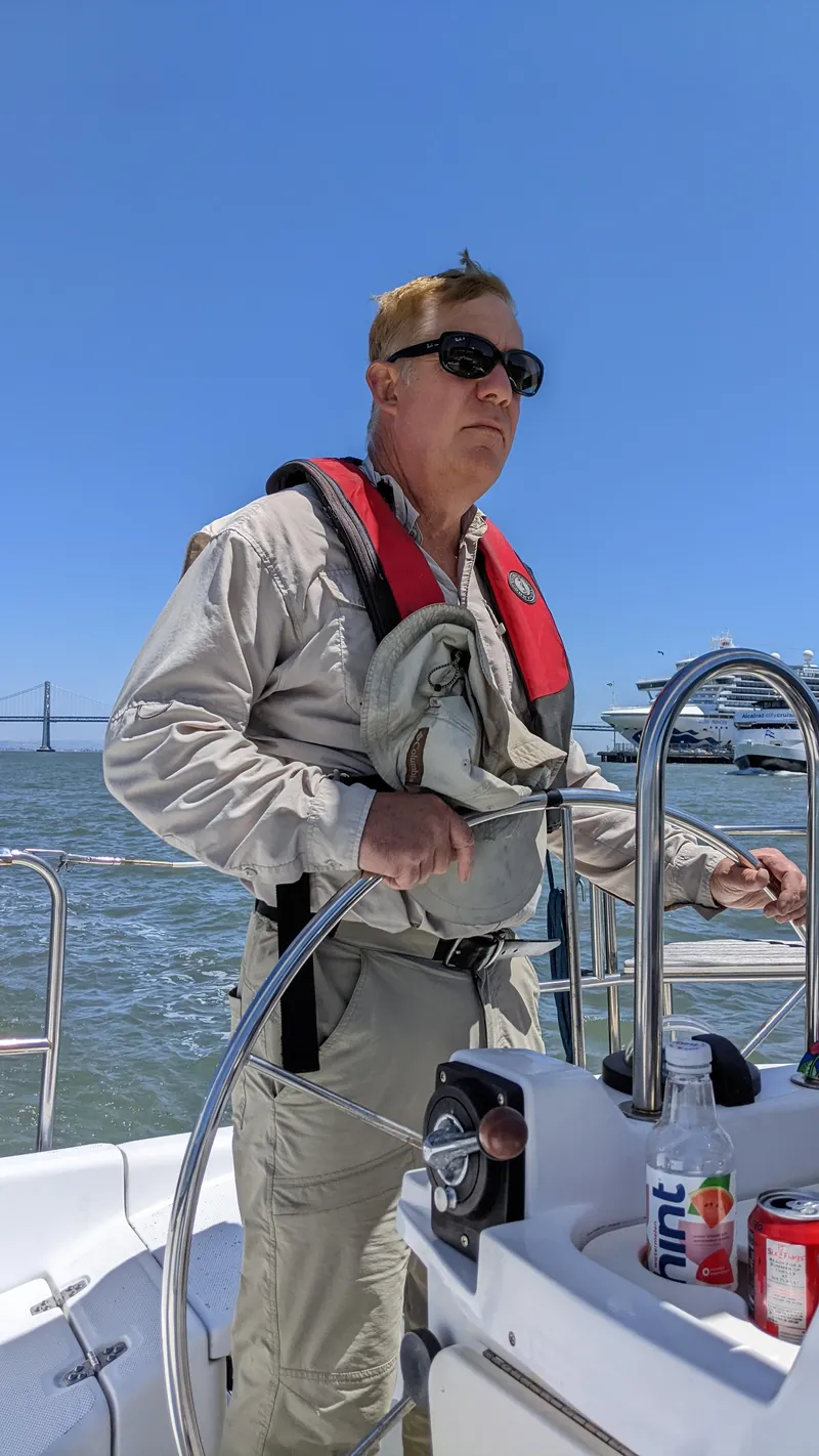 Slide: The Image of Man steering 1999 Hunter 380 sailboat on sunny day, wearing life jacket and sunglasses. - 15