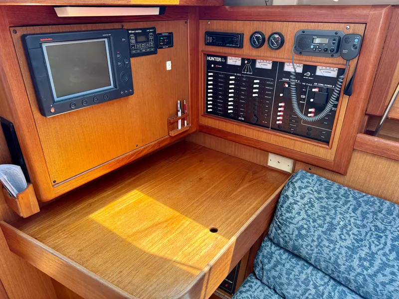 Slide: The Image of Navigation station of a 1999 Hunter 380 sailboat with control panels and seating. - 20