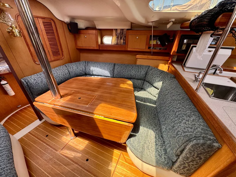 Slide: The Image of Cozy interior of a 1999 Hunter 380 sailboat with wooden table and cushioned seating. - 21