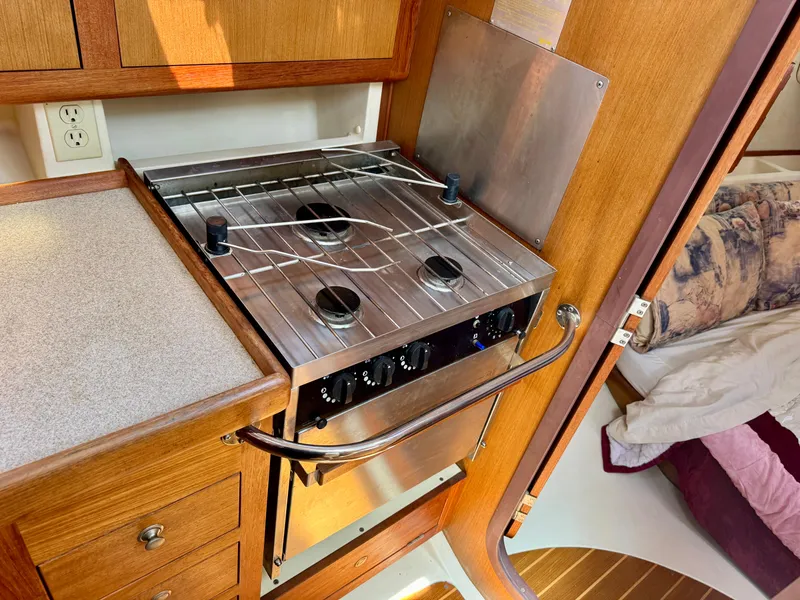 Slide: The Image of 1999 Hunter 380 yacht kitchen with stove, wooden cabinetry, and cozy interior. - 26