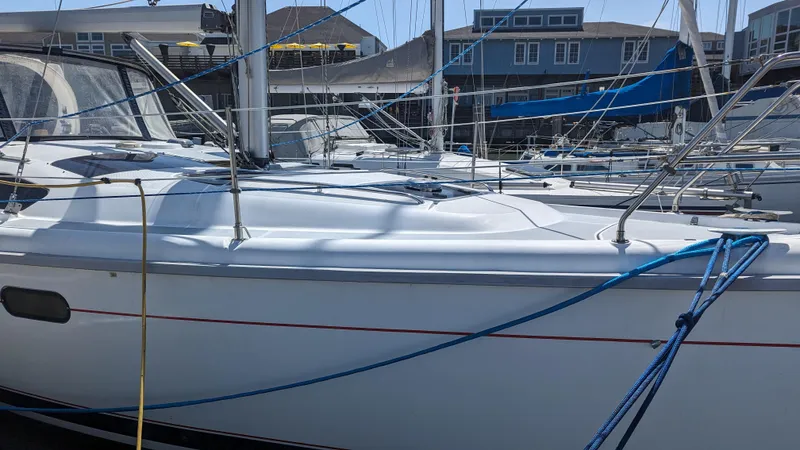 Slide: The Image of 1999 Hunter 380 sailboat docked at marina, featuring sleek white hull and blue ropes. - 3