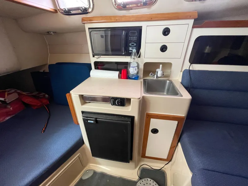 Slide: The Image of Compact kitchen area in a 2004 Albin 30 Family Cruiser with sink, microwave, and mini fridge. - 32