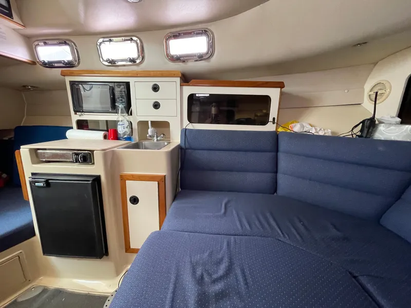Slide: The Image of Interior of a 2004 Albin 30 Family Cruiser with blue seating and compact kitchen area. - 35