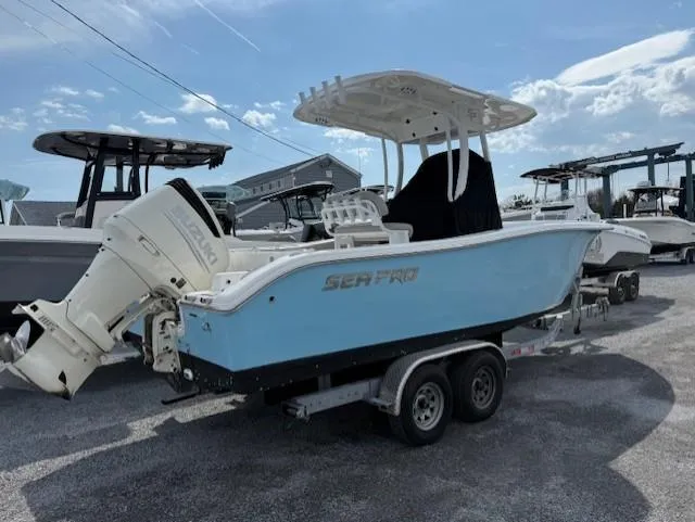 Slide: The Image of 2018 Sea Pro 239 Center Console boat on trailer, light blue hull, parked outdoors. - 2
