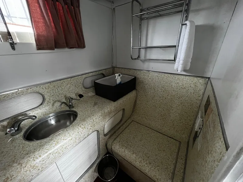 Slide: The Image of 1948 Chris-Craft Double Cabin bathroom with sink, towel rack, and window curtain. - 46