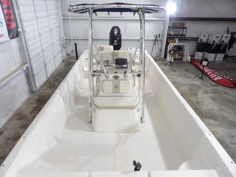 Slide: The Image of 2013 Carolina Skiff 238 DLV boat in a garage, featuring a center console and T-top. - 11