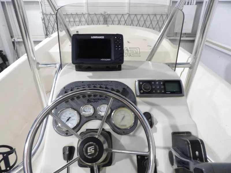 Slide: The Image of 2013 Carolina Skiff 238 DLV boat dashboard with steering wheel and navigation equipment. - 13