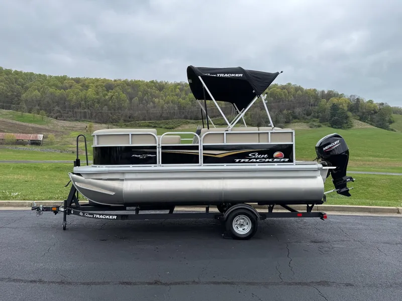 Slide: The Image of 2025 Sun Tracker Party Barge 16 DLX pontoon boat on trailer, scenic background. - 3