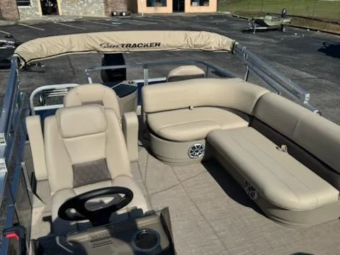 Slide: The Image of 2025 Sun Tracker Bass Buggy 18 DLX pontoon boat interior with beige seating and steering console. - 6