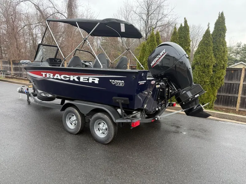 Slide: The Image of 2025 Tracker Targa V-18 Combo boat on trailer, parked outdoors, with Mercury outboard motor. - 4