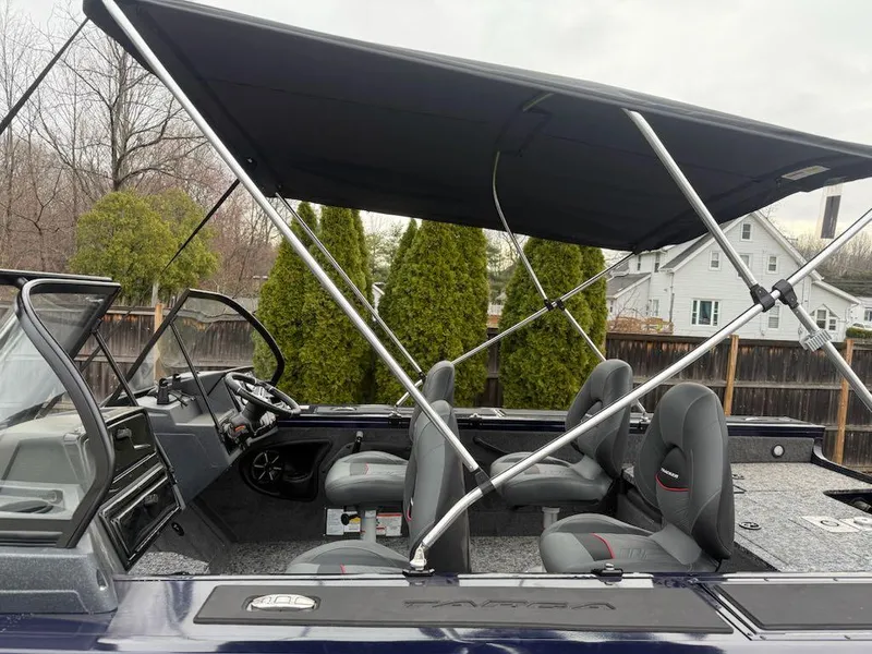 Slide: The Image of 2025 Tracker Targa V-18 Combo boat with canopy and seating, parked outdoors. - 6