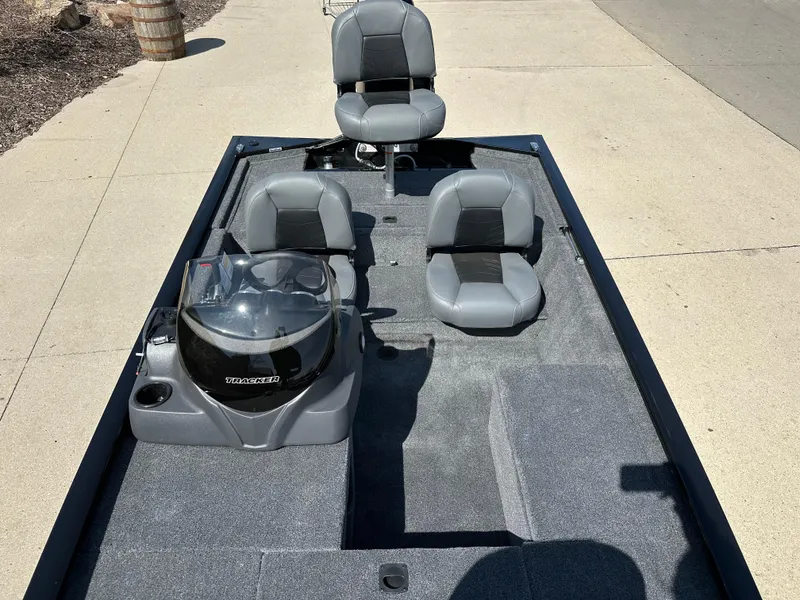 Slide: The Image of 2025 Tracker Pro 170 boat interior with gray seating and console, parked on pavement. - 7