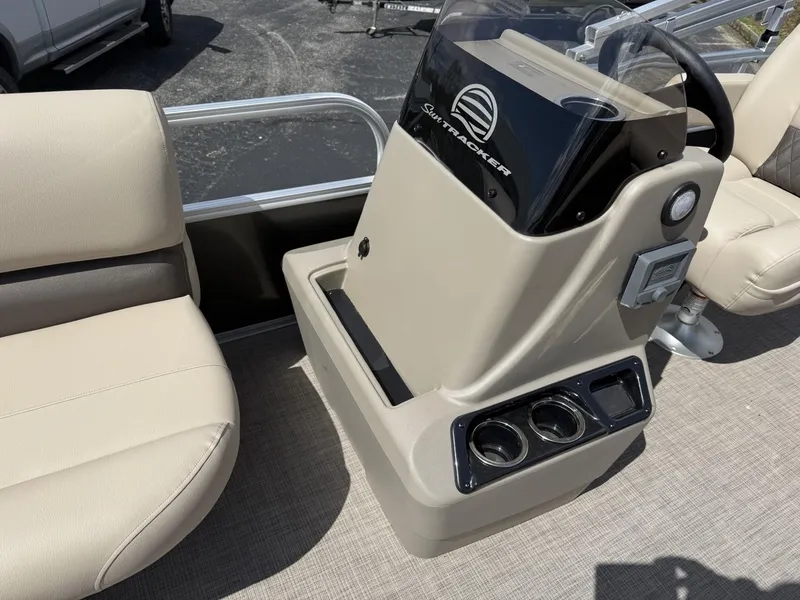Slide: The Image of 2025 Sun Tracker Party Barge 16 DLX helm with beige seating and cup holders. - 11