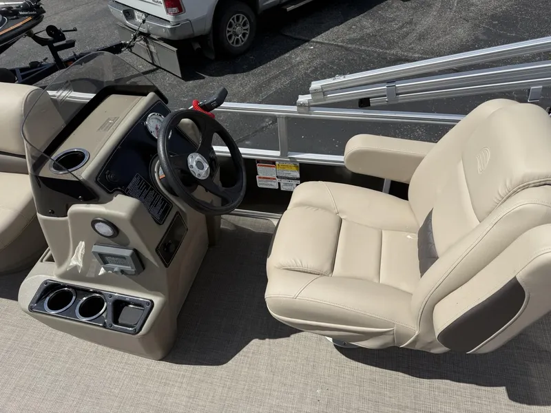 Slide: The Image of 2025 Sun Tracker Party Barge 16 DLX interior with steering console and beige captain's chair. - 7