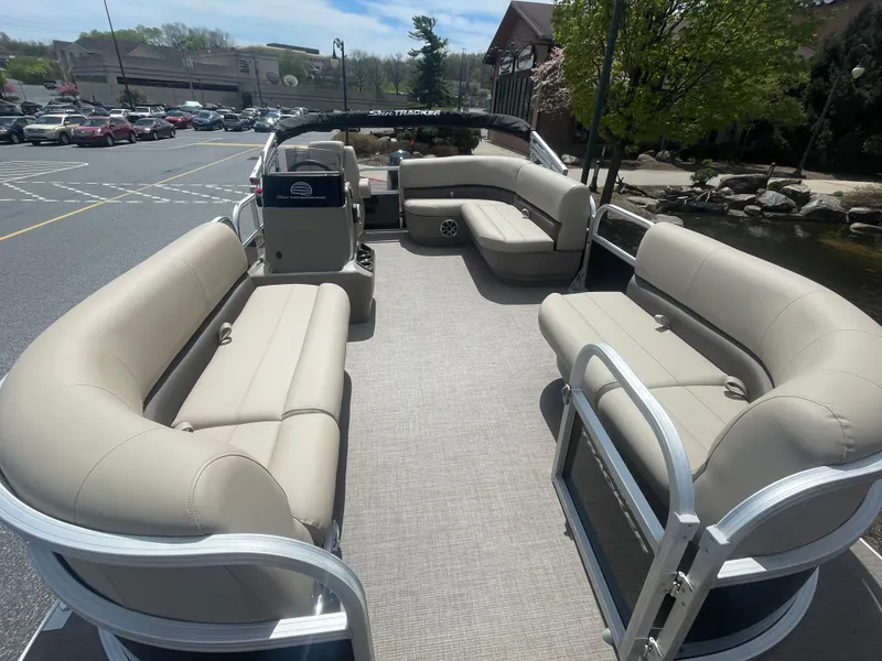 Slide: The Image of 2025 Sun Tracker Party Barge 16 DLX pontoon boat with spacious seating in a parking lot. - 2