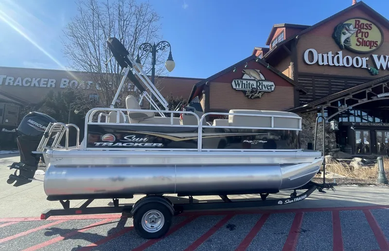 Slide: The Image of 2025 Sun Tracker Party Barge 16 DLX pontoon boat displayed outside Bass Pro Shops. - 3