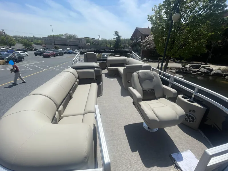 Slide: The Image of 2025 Sun Tracker SportFish 20 DLX pontoon boat with beige seating, parked near a pond. - 2