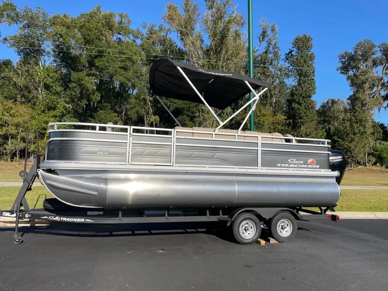 Slide: The Image of 2025 Sun Tracker Party Barge 20 DLX pontoon boat on trailer, parked outdoors. - 3