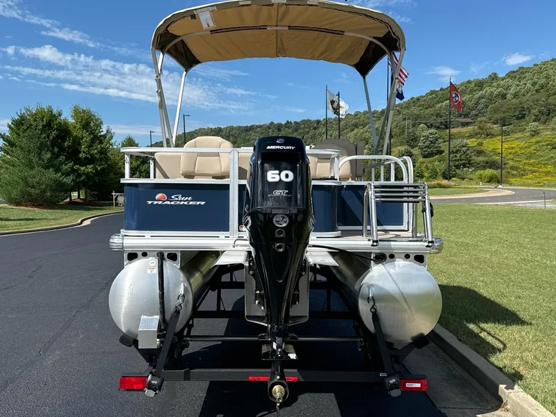 Slide: The Image of 2025 Sun Tracker Bass Buggy 18 DLX pontoon boat with Mercury 60 engine, parked outdoors. - 4