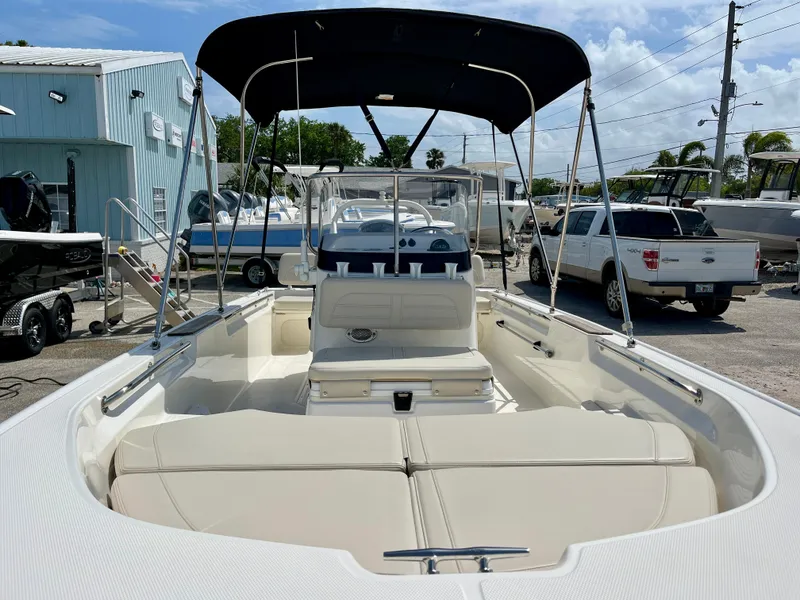 Slide: The Image of 2022 Boston Whaler 17 Montauk boat with canopy, docked in a marina under a clear sky. - 14