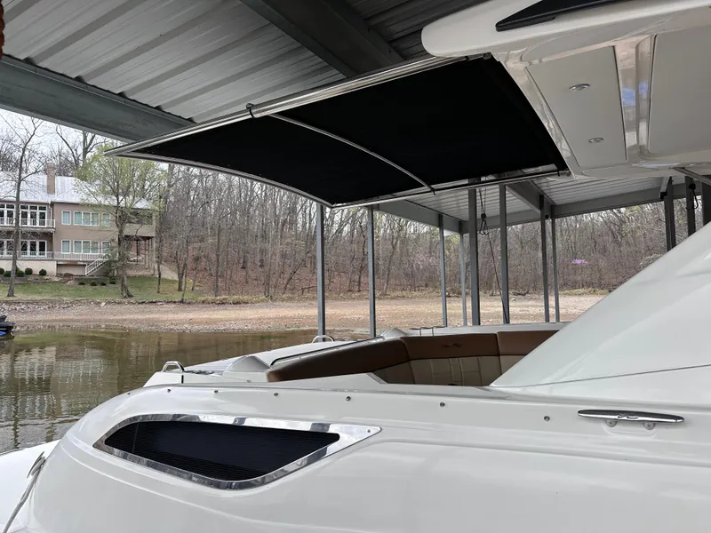Slide: The Image of 2014 Sea Ray 350 SLX boat docked under a covered structure by a wooded lakeside. - 29