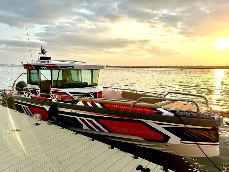 Slide: The Image of 2021 Axopar 28 CABIN boat docked at sunset, featuring sleek red and black design. - 1