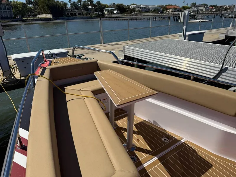 Slide: The Image of 2021 Axopar 28 CABIN boat with tan seating and wooden table, docked by the water. - 10