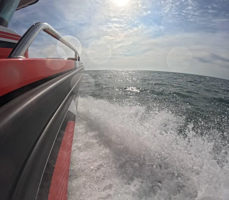 Slide: The Image of Axopar 28 CABIN 2021 cruising on open water under a sunny sky. - 2