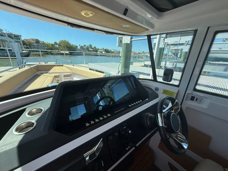 Slide: The Image of Interior view of 2021 Axopar 28 CABIN boat with modern dashboard and waterfront background. - 8