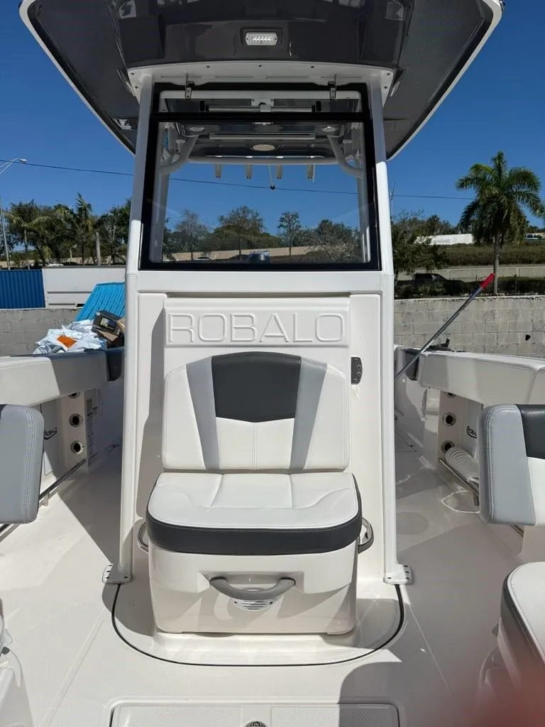 Slide: The Image of 2023 Robalo R250 boat interior with seating and console, under clear blue sky. - 6